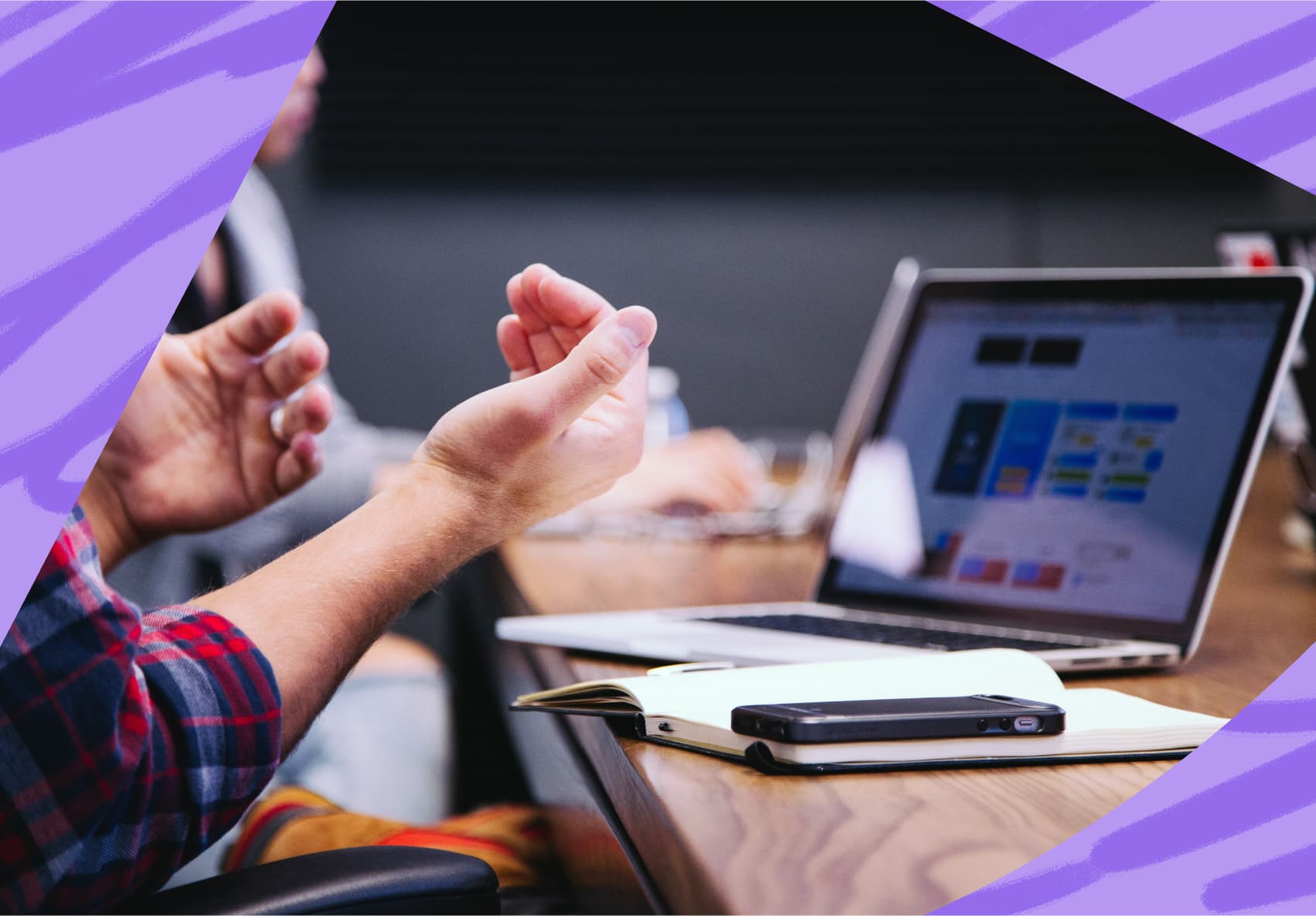Person sitting a desk in a meeting, hands in front of a laptop
