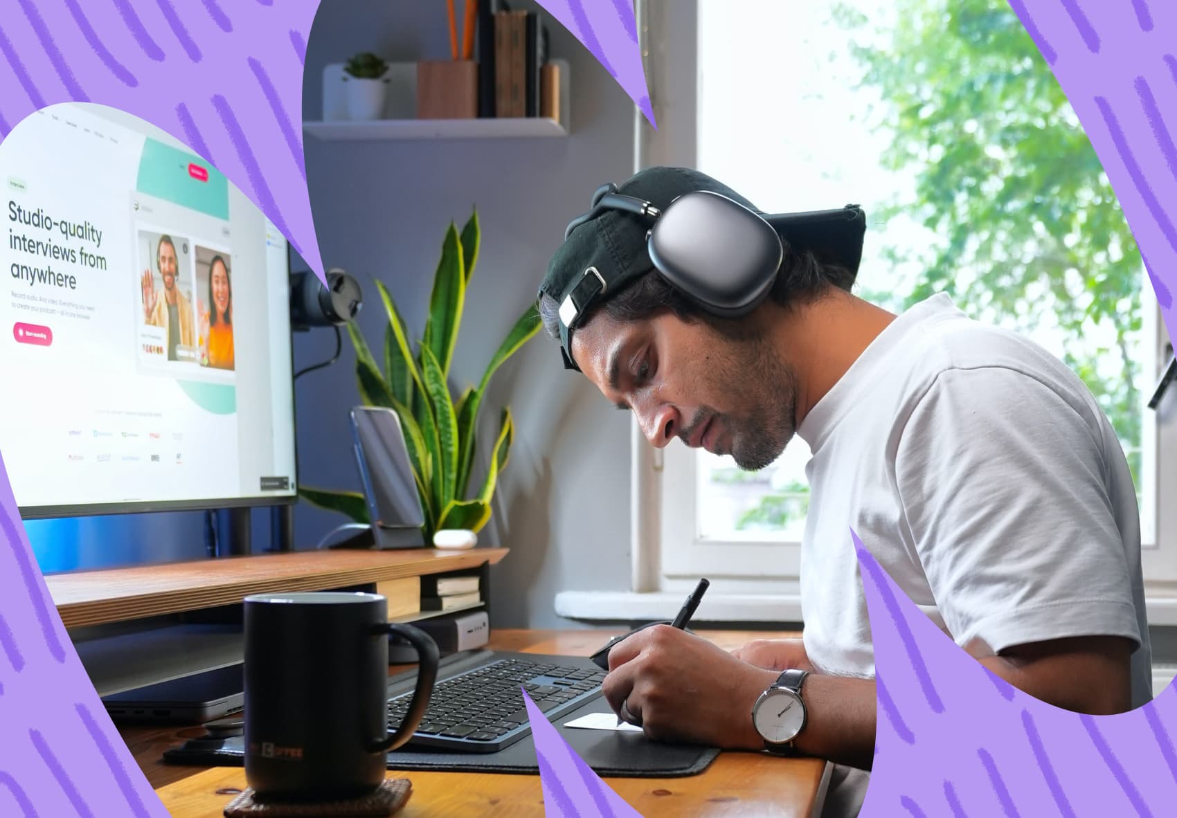 Man with headphones in front of a computer screen, and writing notes